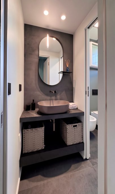 Bagno ospiti contemporaneo con specchio a capsula e lavabo d'appoggio